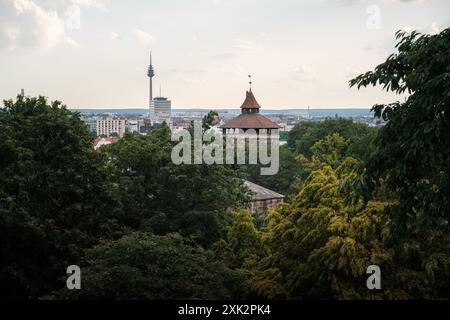 Vista della vecchia torre Neutorturm nel bosco e sullo sfondo della moderna torre di telecomunicazioni nella città tedesca di Norimberga. Foto Stock