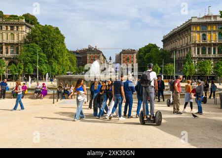 Turisti che camminano e guidano veicoli Segway in Piazza Castello, con sullo sfondo il monumento a Giuseppe Garibaldi, Milano, Lombardia, Italia Foto Stock