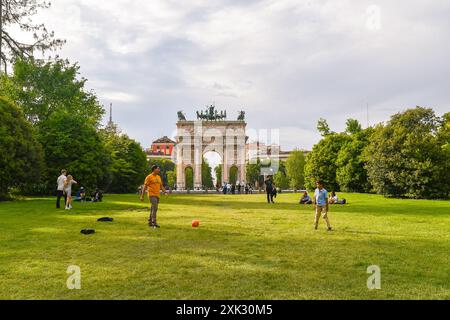 Un uomo e un ragazzo che giocano a palla in un prato del Parco Sempione con l'Arco della Pace sullo sfondo in primavera, Milano, Lombardia, Italia Foto Stock