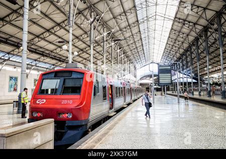 LISBONA, Portogallo - Un treno diretto a Sintra aspetta al binario della storica stazione Rossio di Lisbona. La scena cattura la miscela di architettura ferroviaria del XIX secolo e trasporti moderni, evidenziando il popolare percorso tra la capitale del Portogallo e la pittoresca città di Sintra. Foto Stock