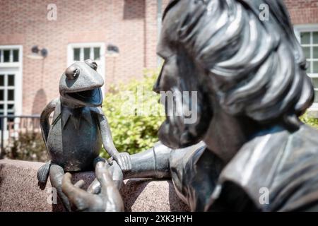 COLLEGE PARK, Maryland, Stati Uniti - il Jim Henson Memorial presso l'Università del Maryland presenta una statua in bronzo del famoso burattinaio con la sua famosa creazione, Kermit the Frog. Henson, un ex allievo dell'Università del Maryland, è raffigurato seduto su una panchina in una posa rilassata. Il memoriale, situato fuori dalla Adele H. Stamp Student Union, onora l'eredità creativa di Henson e il suo legame con l'università. Foto Stock