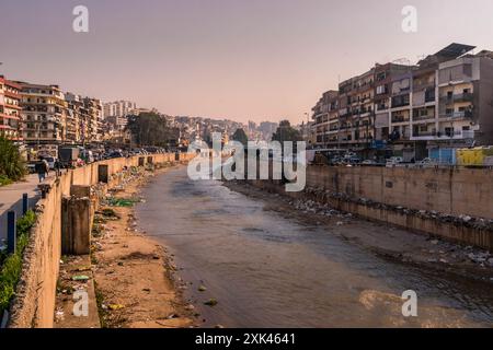 Foto del fiume Abou Ali nel centro di Tripoli, in Libano, con il lungomare sporco e la spazzatura nell'acqua. Foto Stock