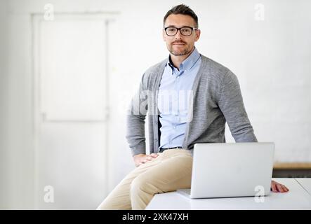 Laptop, ufficio e ritratto di un uomo d'affari con occhiali per il supporto IT in una startup. Sorridi, orgoglio e ingegnere software maschile con computer per Foto Stock