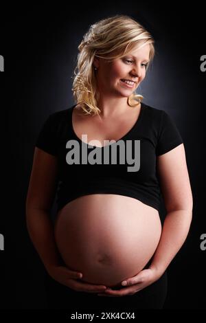 Incinta, madre e pensiero con la pancia in studio, bump bambino e donna in gravidanza. Sfondo nero, gestazione e ginecologia per la crescita dello stomaco Foto Stock