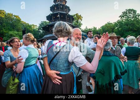 Kocherlball am Chinesischen Turm, hunderte Paare tanzen zur bayerischen Musik, morgens um 6:15 Uhr, München, 21. Juli 2024 Deutschland, München, 21. Juli 2024, hunderte Paare tanzen zur bayerischen Musik, morgens um 6:15 Uhr, eine Dreiviertelstunde nach Sonnenaufgang, Kocherlball am Chinesischen Turm, Englischer Garten, Musikkapelle Quetschnblech spielt auf, Besucher feiern und tanzen Früh morgens zu bayerischer Musik Tradition, tragen Trasik, Trasik 19. Jahrhundert, als Hauspersonal, Dienstboten und KöchInnen in den frühen Morgenstunden vor Dienstbeginn gefeiert und getanzt haben, Tradit Foto Stock