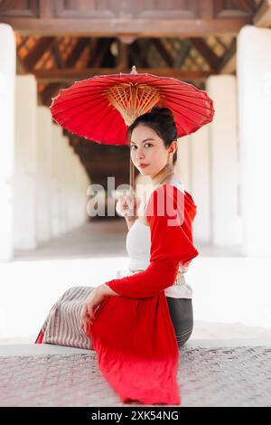 I lanna del nord della Thailandia Chiangmai indossano abiti in stile tradizionale, belle donne vestite vintage con ombrello di carta al wat ton kwen. Foto Stock