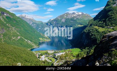 Geiranger Fjord Norvegia, Una splendida vista di un fiordo norvegese circondato da lussureggianti montagne verdi, con una piccola cittadina annidata nella valle sottostante. Foto Stock