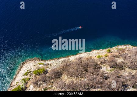 Una piccola barca con turisti galleggia lentamente su acque limpide. Costa incredibile. Fotografia aerea. Le montagne sono ricoperte di verde, il blu tran Foto Stock