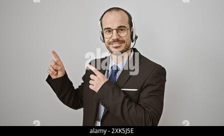 Un uomo sorridente con la cuffia e la tuta si muove positivamente su uno sfondo bianco. Foto Stock