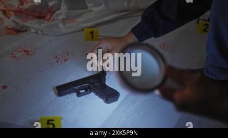 Detective afroamericano che analizza le prove su una scena del crimine al chiuso con sangue, arma, lente d'ingrandimento e marcatori numerati. Foto Stock