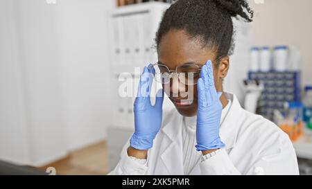 Scienziata afroamericana che regola gli occhiali in laboratorio Foto Stock