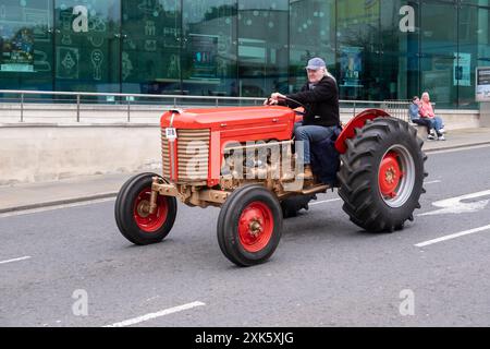 Ballymena, Irlanda del Nord - 19 luglio 2024: Rally di trattori d'epoca, trattori rossi e dorati guidati oltre il municipio di Bridge Street. Foto Stock