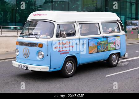 Ballymena, Irlanda del Nord - 19 luglio 2024: Camper VW retro originale blu e bianco che attraversa la città con pannelli laterali artistici. Foto Stock