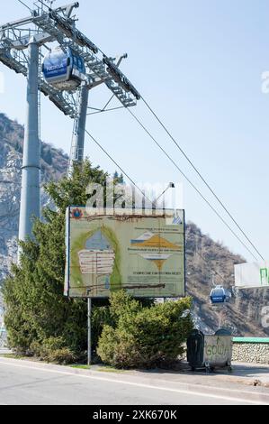 Kazakistan, Almaty, 18 aprile 2012. Pannello esplicativo sulla diga di controllo del flusso di fango Medeu con la funivia che passa sopra Foto Stock