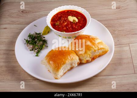 Il PAV Bhaji è un fast food indiano, con curry vegetale denso e piccante, fritto e servito con pane morbido, Bun Pav e burro. messa a fuoco selettiva Foto Stock