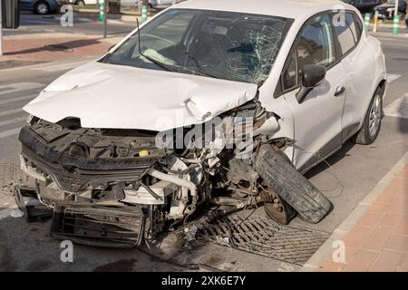 Vettura bianca gravemente danneggiata dopo un incidente, che mostra il parabrezza frantumato e la carrozzeria deformata. Ideale per l'uso in materiali correlati al veicolo Foto Stock