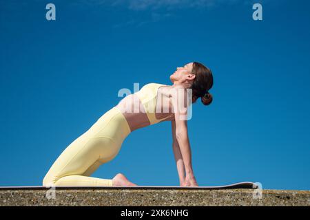 Donna sportiva che indossa un cammello all'aperto, abbigliamento sportivo giallo Foto Stock