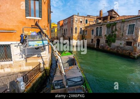 Venezia, Italia - 4 giugno 2024: Raccolta rifiuti a Venezia. Edifici sul Canal grande, con battello per la raccolta dei rifiuti. The Migrant Child art di Banksy on Th Foto Stock