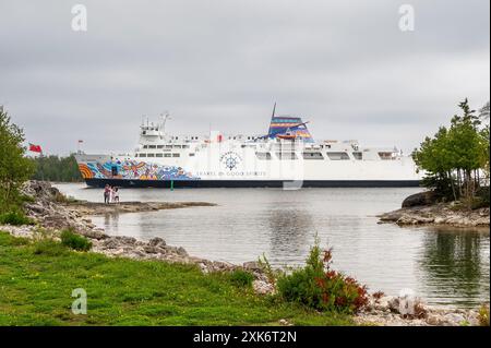 Traghetto chi-Cheemaun che arriva a South Baymouth da Tobermory con alcuni turisti che si affacciano sulla costa. Foto Stock