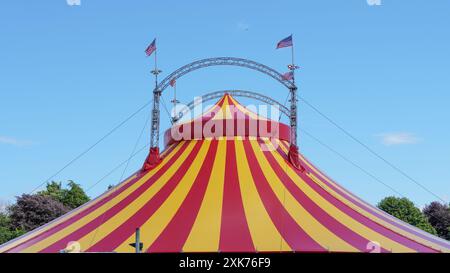 Bridgend, Galles - 7 luglio 2024: Grande top giallo e rosso del circo dai colori vivaci. Le funi di guida o di tipo aumentano la stabilità strutturale o Foto Stock