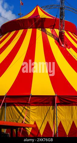 Bridgend, Galles - 7 luglio 2024: Grande top giallo e rosso del circo dai colori vivaci. Le funi di guida o di tipo aumentano la stabilità strutturale o Foto Stock