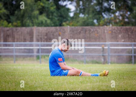 Il basso calciatore siede da solo in campo con la testa inchinata e si sente molto depresso Foto Stock