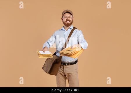 Felice giovane postino con borsa in pelle che consegna lettere su sfondo marrone Foto Stock