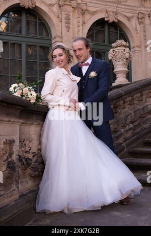 Una sposa carina in abito con un treno e uno sposo che posa sui gradini di un bellissimo palazzo. Servizio fotografico per matrimoni Foto Stock