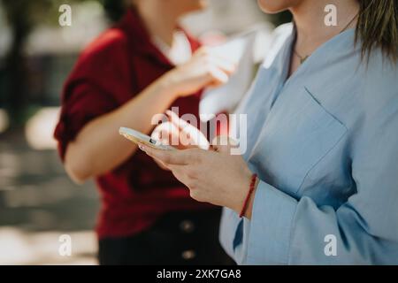 Partner aziendali che comunicano all'aperto in città utilizzando uno smartphone Foto Stock