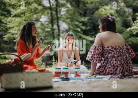 Gli amici si godono un picnic nella natura giocando a carte e rilassandosi all'aperto Foto Stock