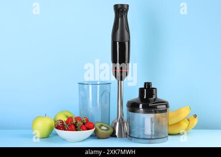 Kit frullatore a immersione, frutta fresca e fragole su sfondo azzurro Foto Stock