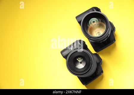 Due fotocamere moderne su sfondo giallo, vista dall'alto. Spazio per il testo Foto Stock