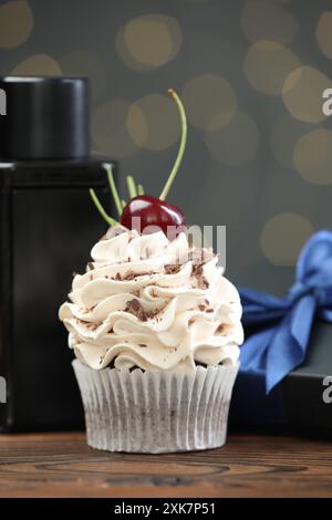 Buona festa del papà. Cupcake, confezione regalo e profumo sul tavolo di legno contro luci sfocate e primo piano Foto Stock