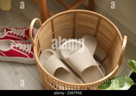 Cestino con pantofole per gli ospiti e scarpe da ginnastica all'ingresso di casa Foto Stock