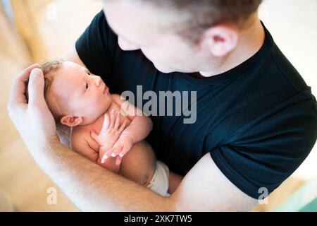 Padre che tiene in braccio il suo bambino appena nato. Amore paterno incondizionato, concetto di festa del papà. Foto Stock