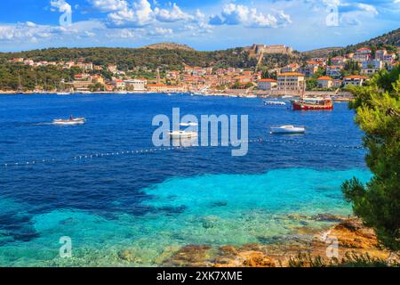 Paesaggio estivo costiero - vista della città di Hvar e della fortezza spagnola sopra di essa, sull'isola di Hvar, la costa adriatica della Croazia Foto Stock