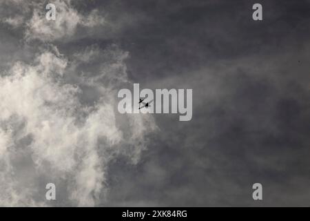 Un piccolo aereo ad elica che vola in alto nel cielo contro un cielo grigio e nuvole bianche simili a fumo. Un'immagine cupa. Foto di alta qualità Foto Stock
