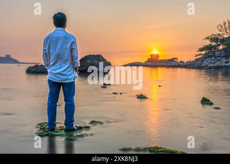 Il paesaggio dell'alba a Hon Chong attira la gente ad allenarsi lungo la spiaggia in una mattina d'estate a Nha Trang, Vietnam Foto Stock