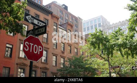 Incrocio a senso unico a New York City, incrocio di Stuyvesant Street, freccia a senso unico. Edificio residenziale Manhattan Midtown, edificio architettonico, immobiliare degli Stati Uniti. Muro della casa in mattoni rossi, segnale di stop rosso. Foto Stock