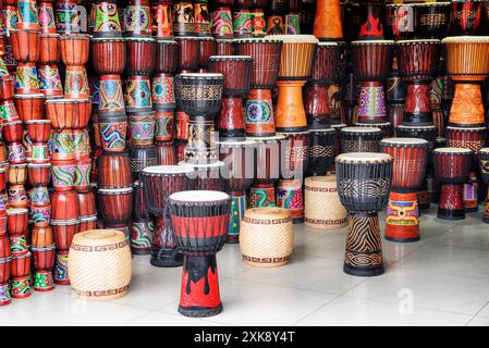 Ampia gamma di tamburi colorati in legno di djembe presso il negozio di souvenir Foto Stock