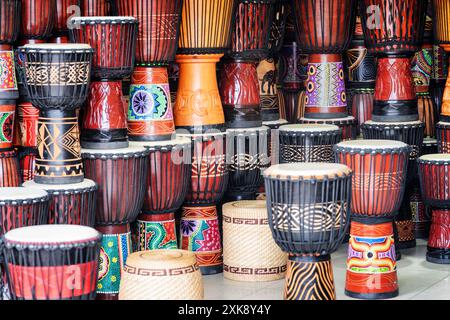 Scenografiche file di tamburi di djembe colorati in legno presso il negozio di souvenir Foto Stock