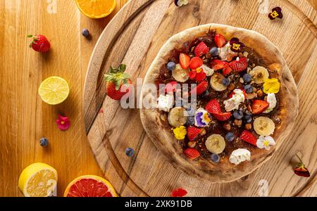 Vista dall'alto di una pizza dolce da dessert condita con frutta fresca e frutti di bosco su un rustico tavolo di legno Foto Stock