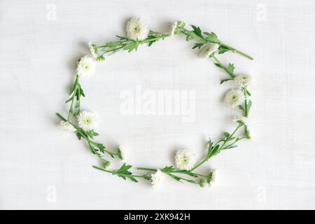 Ghirlanda di fiori bianchi su sfondo di legno bianco Foto Stock