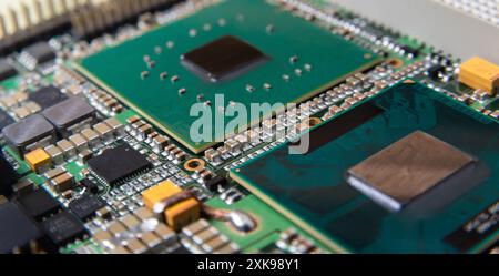 Primo piano dettagliato di una scheda a circuito stampato elettronica che mostra microchip, resistori e altri componenti, che rappresentano la tecnologia e l'hardware moderni. Foto Stock