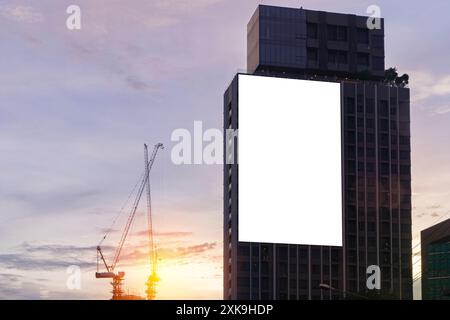 Mock-up cartellone su sfondo bianco sull'edificio, percorso di ritaglio per Mockup. Un grande cartellone vuoto sullo sfondo di una città nel bel mezzo del tramonto. Foto Stock