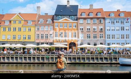 Copenaghen Danimarca 21 luglio 2024, Un viaggiatore solitario contempla il paesaggio urbano mentre si gode una vista sui canali di Copenaghen e sui caffè sul lungomare. Foto Stock