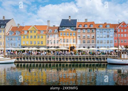 Copenaghen Danimarca 21 luglio 2024, Una vivace scena sul lungomare di Copenaghen, Danimarca, con edifici colorati, caffetterie e barche. Foto Stock