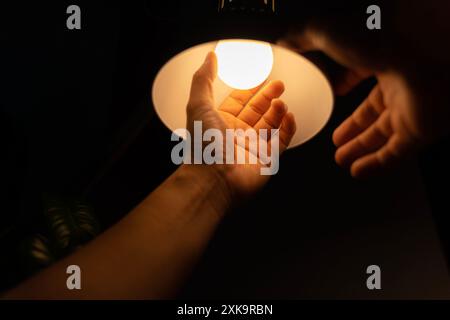 Il tuttofare può scegliere tra risparmio energetico e lampada a incandescenza economica mentre cambia luce nell'appartamento. Sostituzione della lampadina a LED elettrica in Light at ho Foto Stock