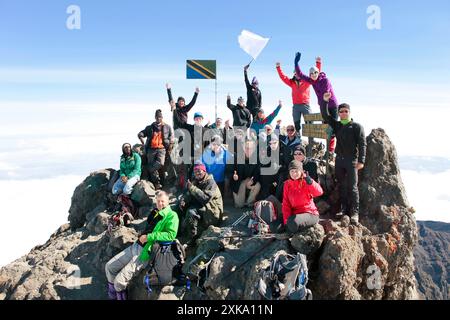 Un gruppo di escursionisti è felice e festeggia sulla cima del Monte Meru, una montagna di trekking in Africa, vicino al Kilimanjaro. Foto Stock