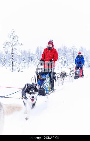 Coppia felice sorridente alla slitta trainata da cani nel paesaggio innevato Foto Stock